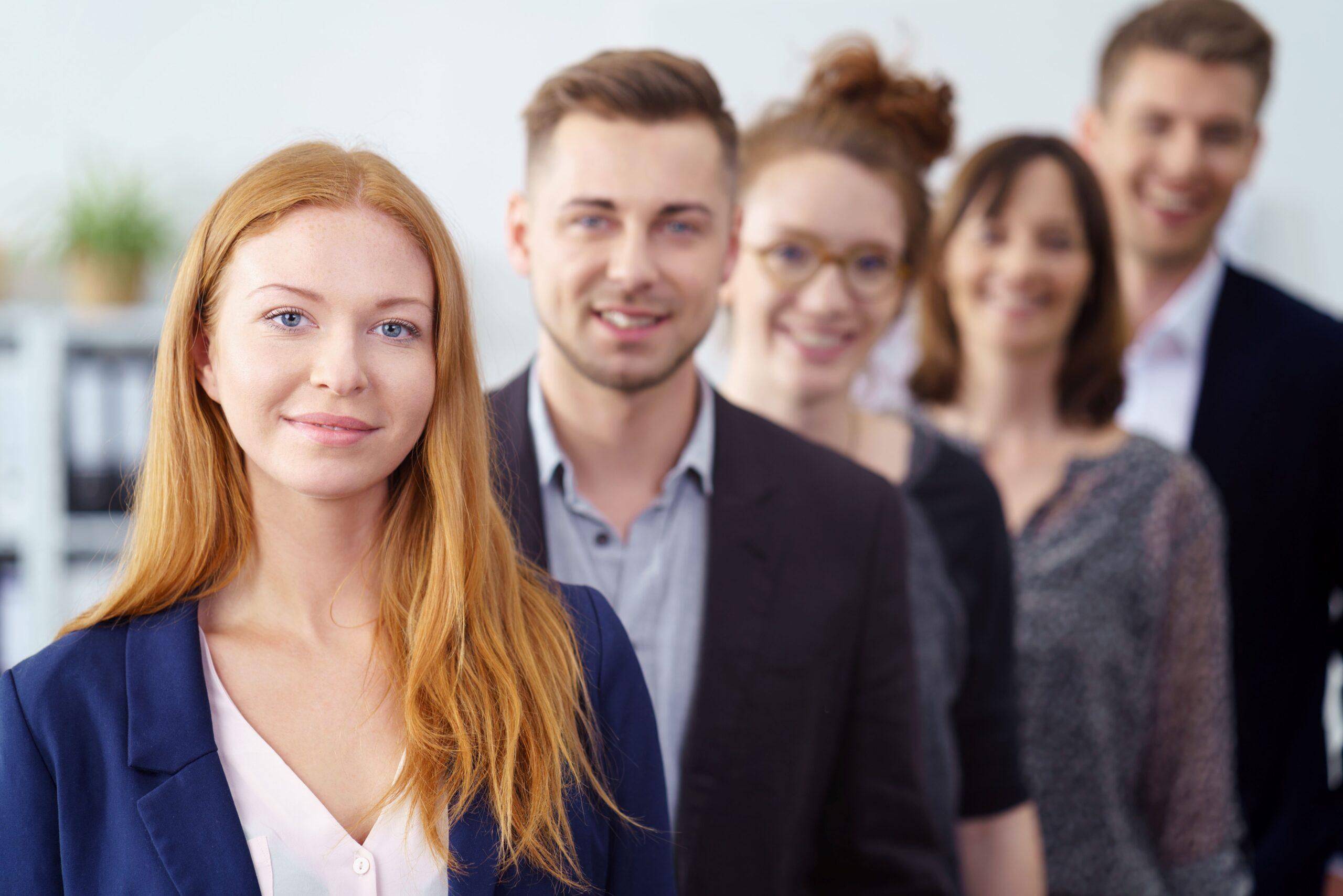 Mehrere Personen stehen in einer Reihe hintereinander. Sie sind alle gut angezogen für die Arbeit 
