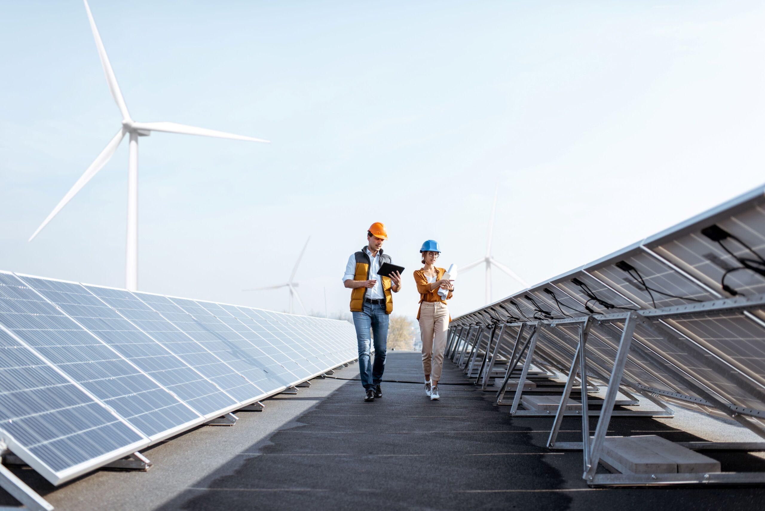 Zwei Personen laufen zwischen zwei Solaranlagen vorbei und kontrollieren etwas