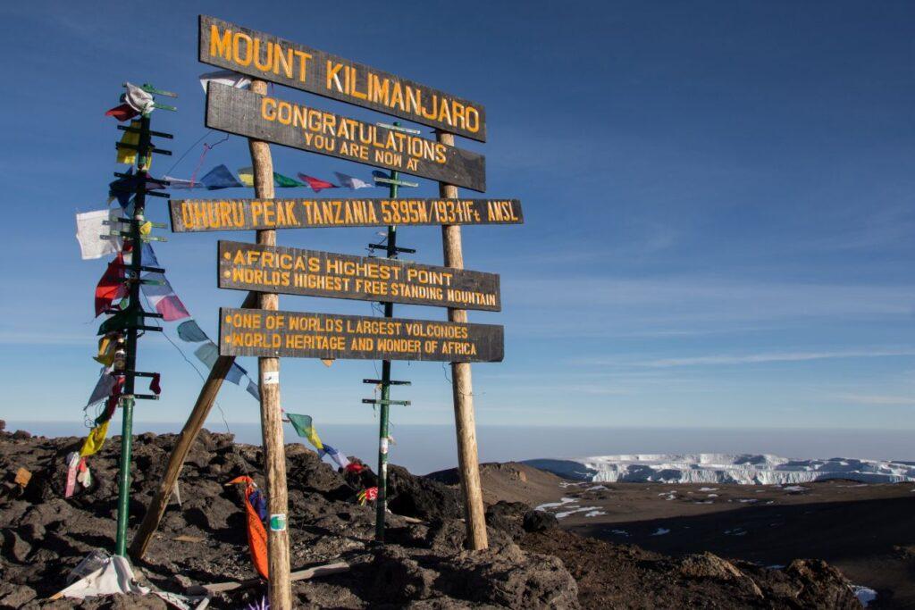 Gipfelschild am Uhuru Peak des Kilimanjaro, das Afrikas höchsten Punkt markiert. Informationen zu Kilimanjaro Besteigung Kosten und Planung.