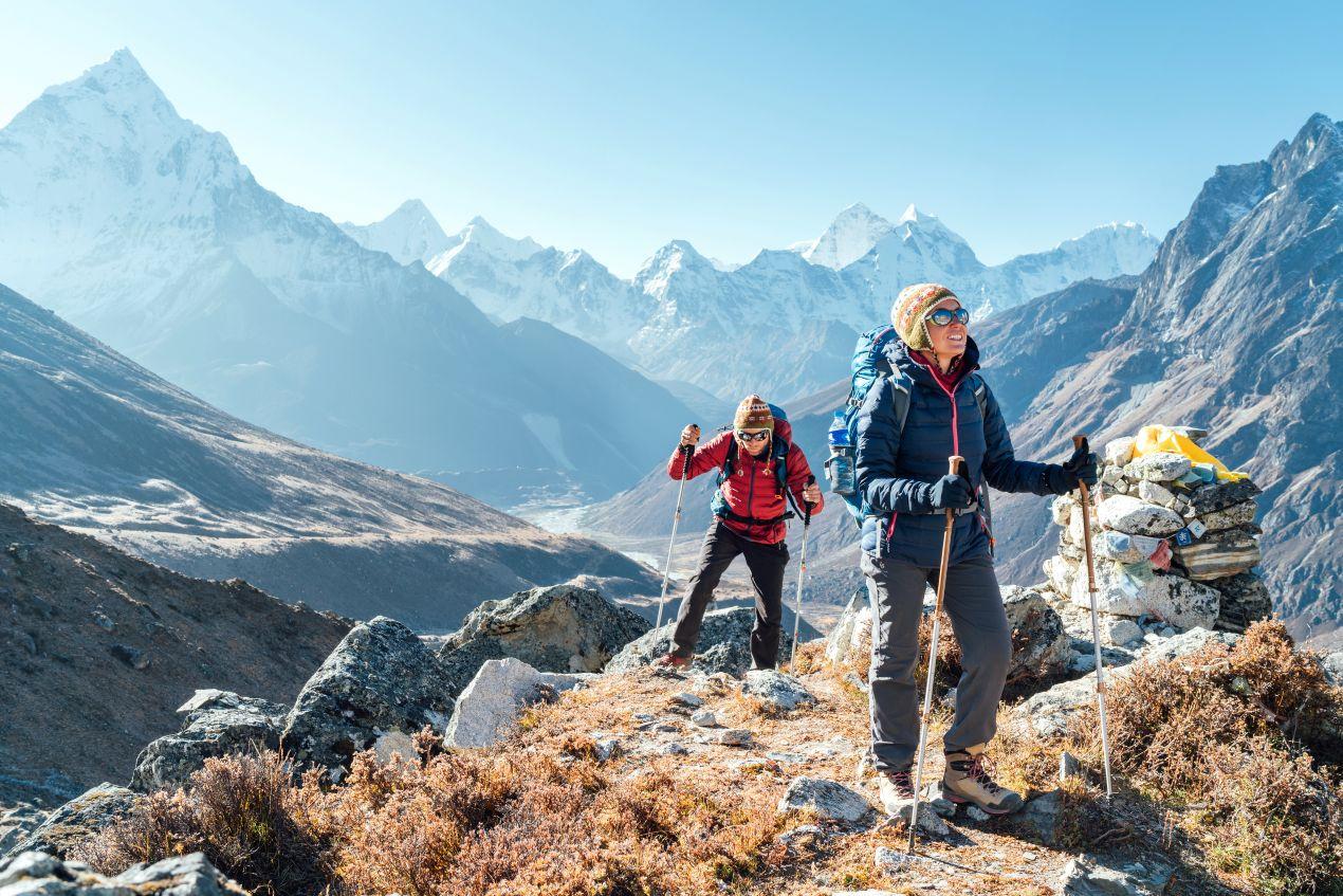 Zwei Wanderer mit Trekking-Ausrüstung auf einer Route des Kilimanjaro, umgeben von Berglandschaft. Tipps zu Kilimanjaro Besteigung Kosten und Ausrüstung.